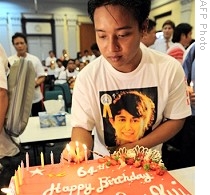 Burmese national places a candle on the 64th birthday cake for detained opposition leader Aung San Suu Kyi in Kuala Lumpur, 19 Jun 2009